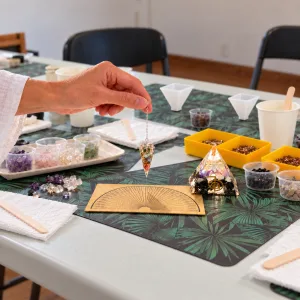 Pendule orgonite et pyramide orgonite de 5 cm OrgoNath réels, présentés avec une planche de radiesthésie dans un environnement généré par IA.